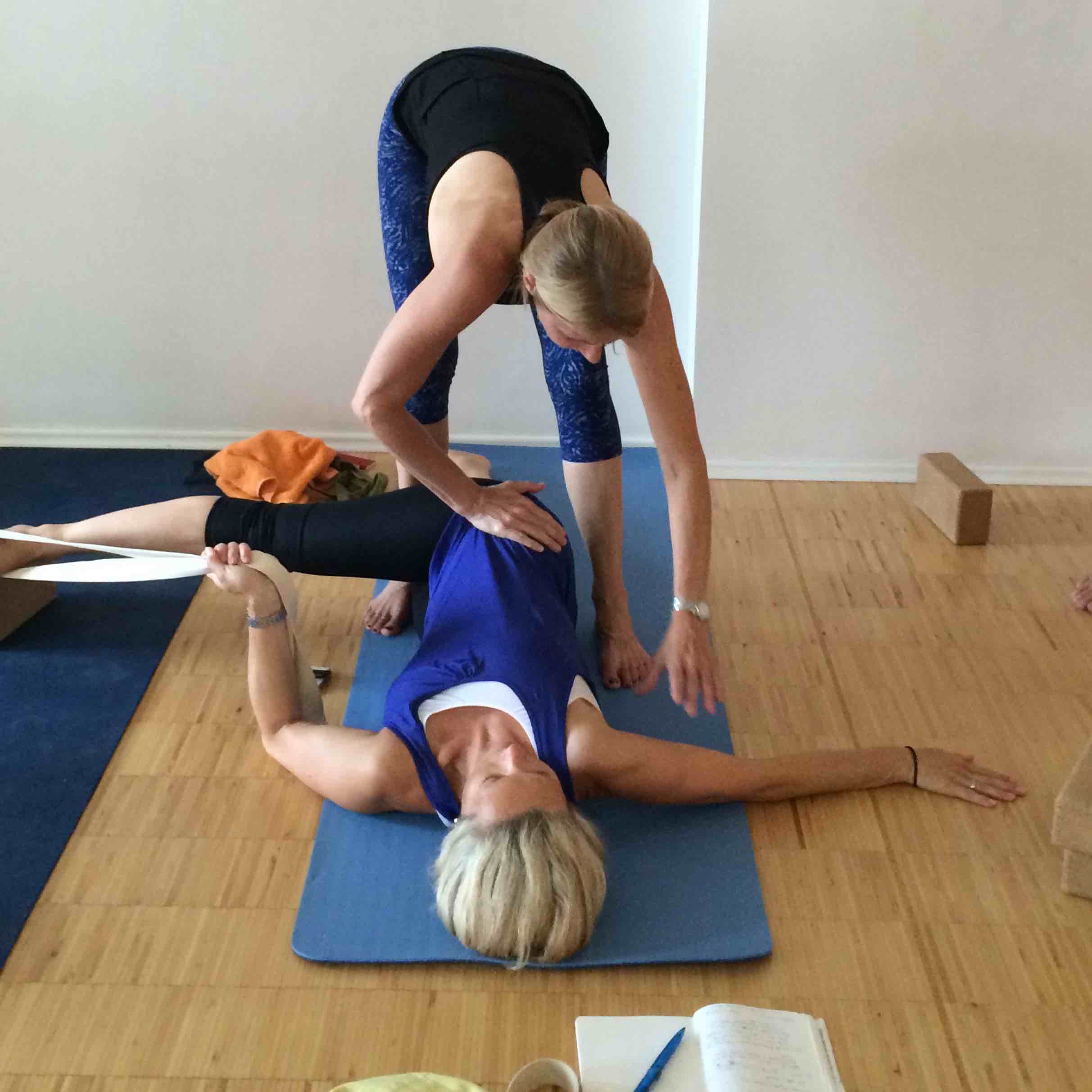 erika helping yoga student in a laying down pose