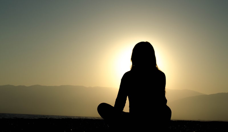 woman meditating silhouette in sunlight